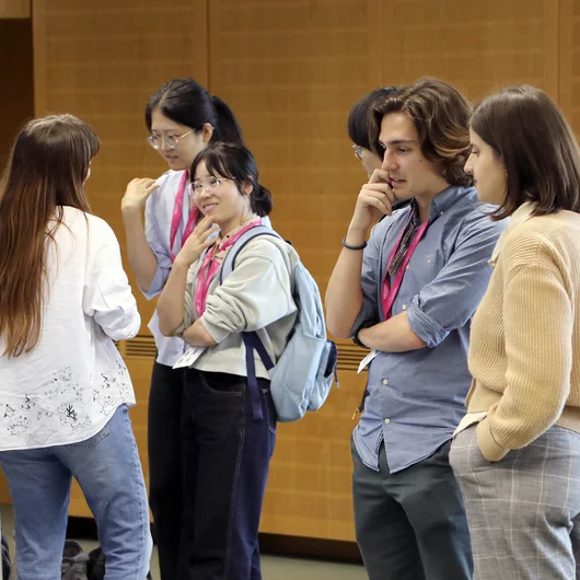 Gruppe junger Wissenschaftlerinnen und Wissenschaftler diskutiert vor einem Forschungsposter.