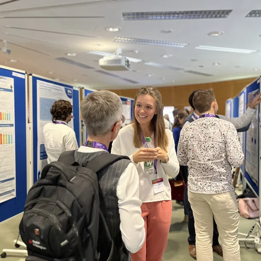 Junge Forscherin im Gespräch mit einer Teilnehmerin während einer Poster-Session auf der Konferenz.